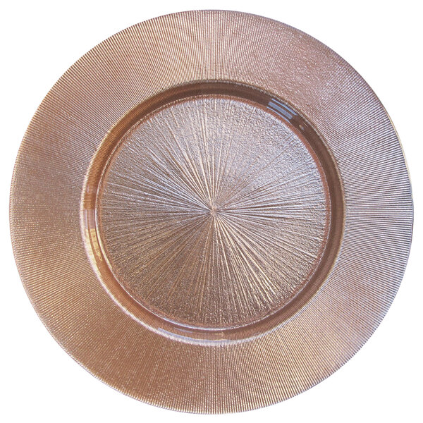 A close-up of a round rose gold glass charger plate with a circular design.