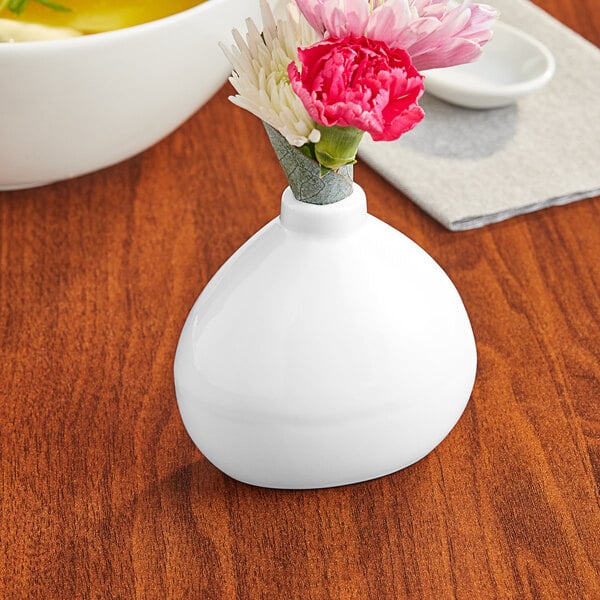 An Acopa bright white round vase with pink and white flowers in it.