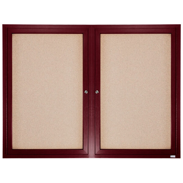 Aarco cherry wood enclosed bulletin board with two doors over cork board.
