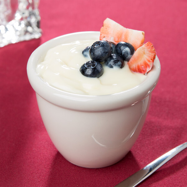 A Hall China ivory custard cup filled with yogurt and berries.