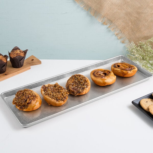 A Chicago Metallic textured silver bakery display tray with pastries on it.