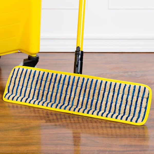 A yellow Rubbermaid HYGEN microfiber mop pad with blue corners on a wood floor.