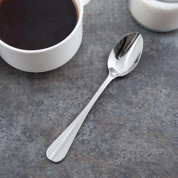 A Libbey stainless steel teaspoon in a cup of coffee on a table.