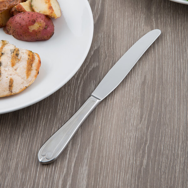 A plate of food with a Libbey Antique stainless steel dinner knife on it.