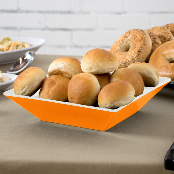A tray of bread in a GET Sunset Square Melamine bowl on a table with a spoon.