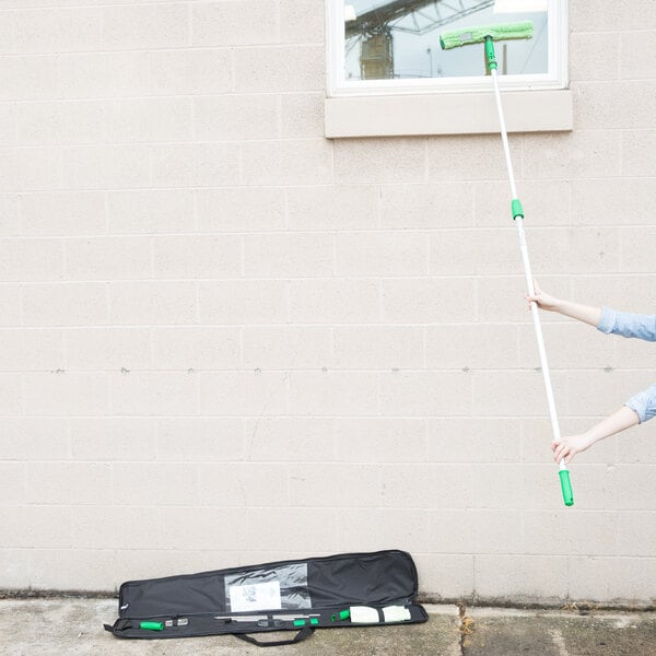 A woman using an Unger ErgoTec window cleaning pole to clean a window.