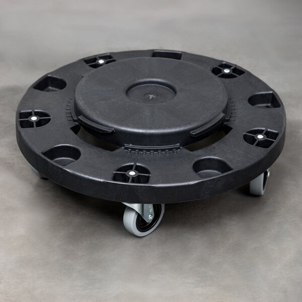 A Carlisle black plastic round trash can dolly with wheels.