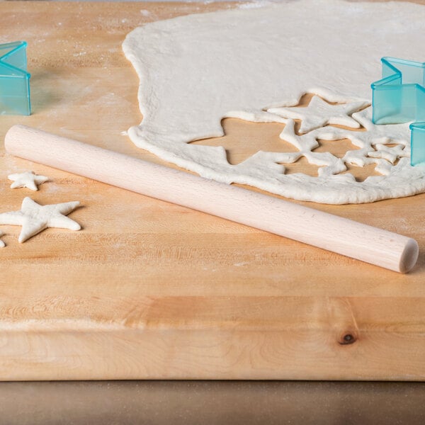 A Thunder Group wood Asian rolling pin and dough with stars cut out on a wooden surface.