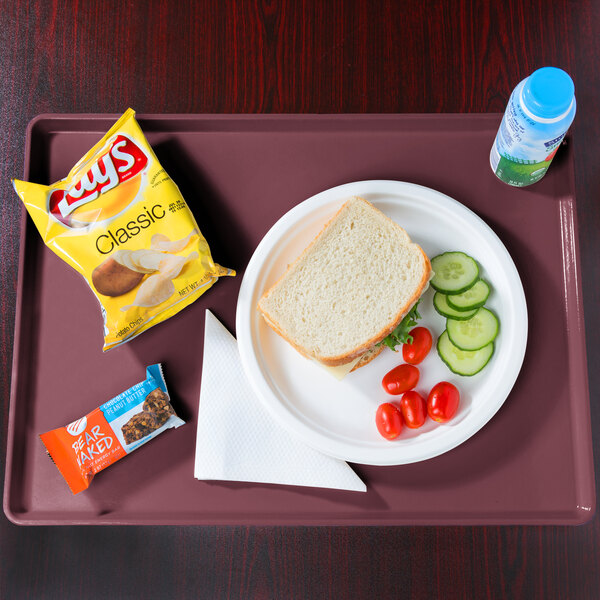 A Cambro dietary tray with a plate of food, a sandwich, and a bottle of chips.