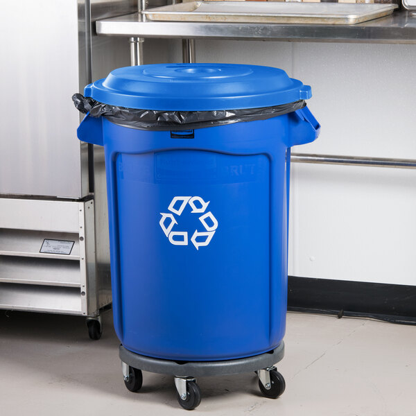 A blue Rubbermaid BRUTE recycling can with dolly and lid with hole for recycling.