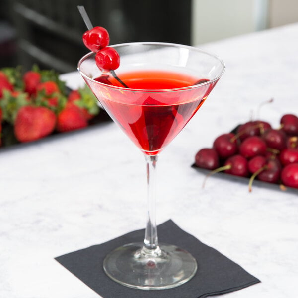 A Libbey martini glass of red liquid with cherries on top.
