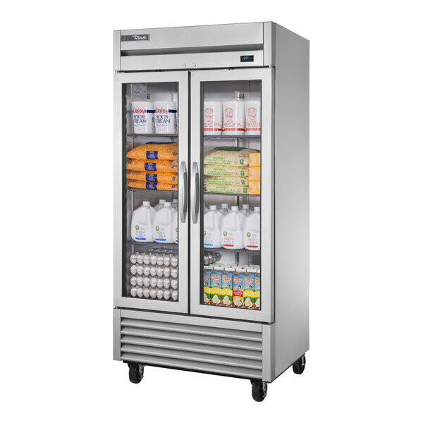 A True 2 section glass door reach-in refrigerator with dairy products and milk.
