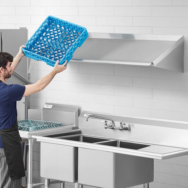 A man in a blue shirt using Regency wall mounted shelves over a stainless steel sink.