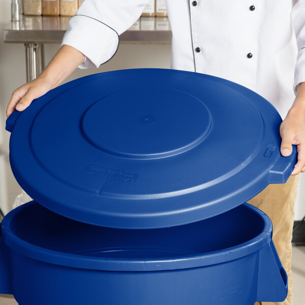 A person holding a blue Carlisle Bronco trash can lid.