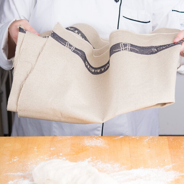 A person holding a Matfer Bourgeat baker's couche with dough on it.