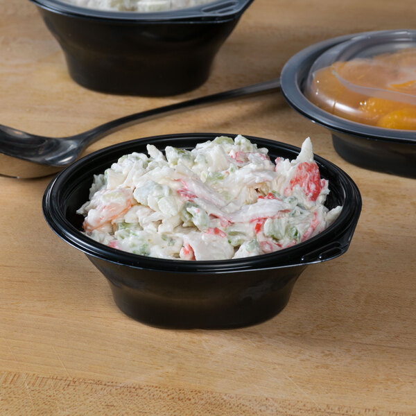 A Fabri-Kal microwaveable side dish bowl filled with food with a plastic lid.