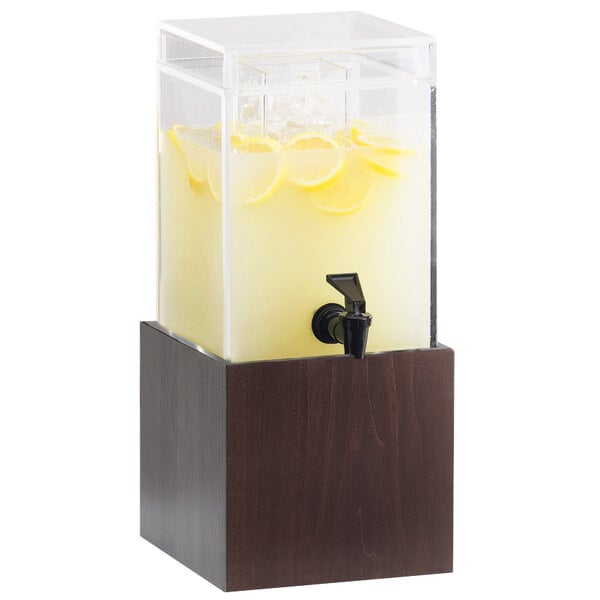 A Cal-Mil dark wood beverage dispenser with a black spigot filled with water and lemon slices.