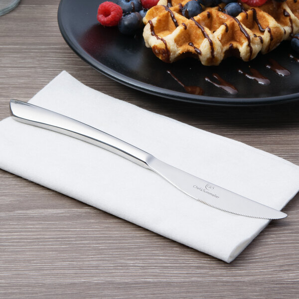A silver Chef & Sommelier Kya stainless steel dessert knife next to a plate of waffles.