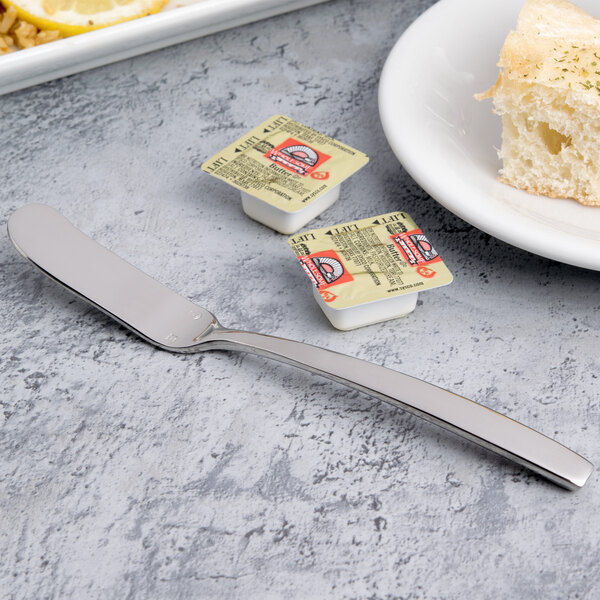 A plate with food next to a Chef & Sommelier stainless steel butter knife.