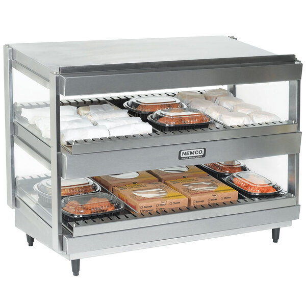 A Nemco stainless steel slanted double shelf countertop food warmer with food trays on a rack.