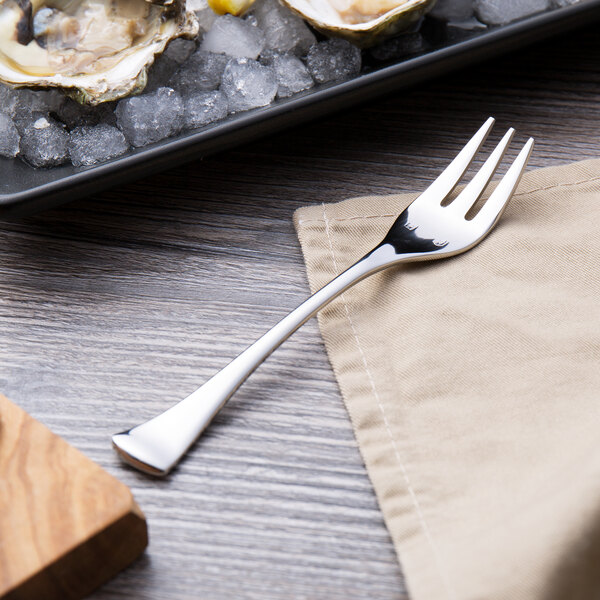 A Chef & Sommelier stainless steel cocktail fork with oysters on a plate of ice.