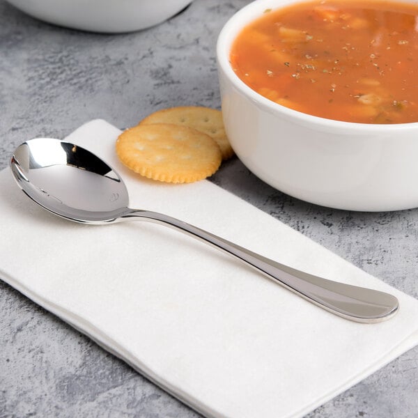 A bowl of soup with crackers and a Chef & Sommelier Renzo stainless steel soup spoon.