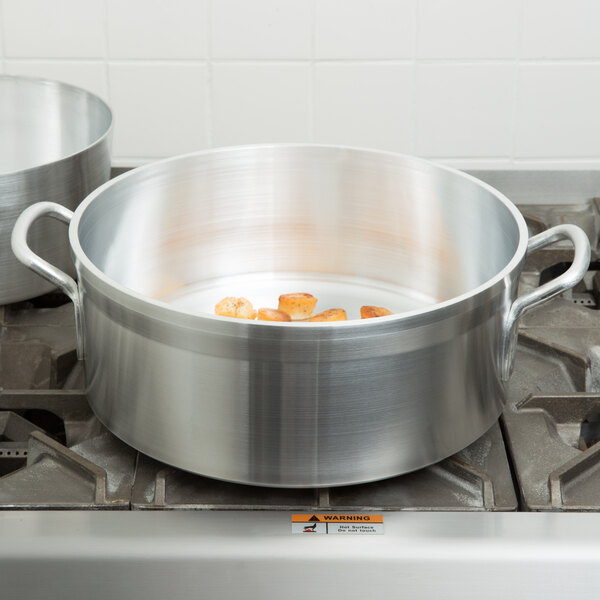 A Vollrath Wear-Ever silver aluminum brazier pot on a stove.