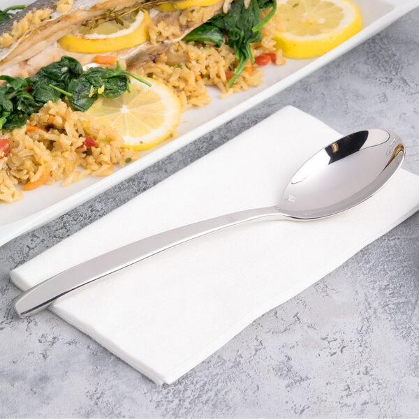A plate of food with a Chef & Sommelier stainless steel dinner spoon and a lemon slice.