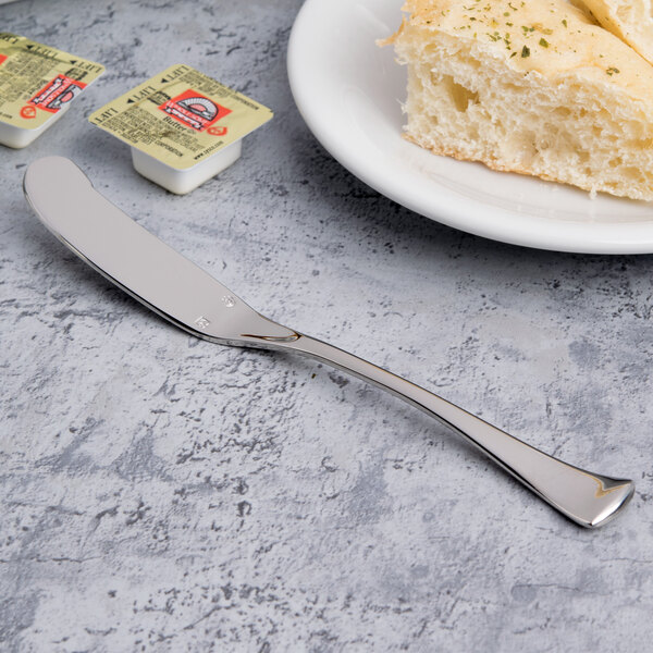 A Chef & Sommelier stainless steel butter spreader on a plate with bread.