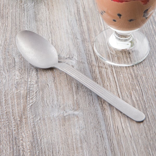 A Libbey stainless steel dessert spoon next to a glass of ice cream.