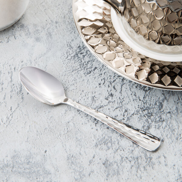 A Libbey stainless steel demitasse spoon on a saucer.