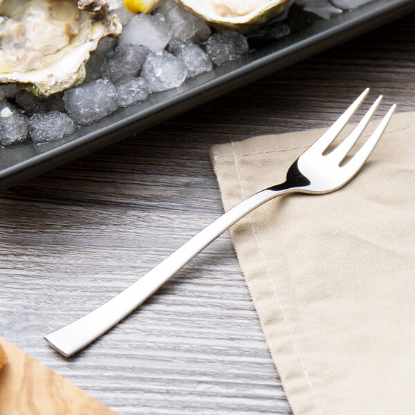 An Arcoroc stainless steel oyster fork on a plate of ice with oysters.