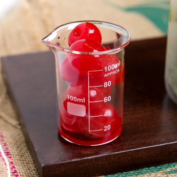 An American Metalcraft beaker glass filled with red liquid and cherries.