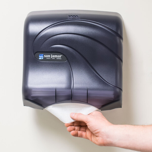 A hand using a San Jamar Black Pearl paper towel dispenser.