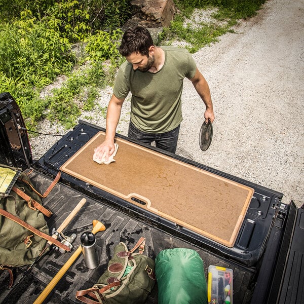 A man cleaning the back of a truck with an Epicurean cutting board.