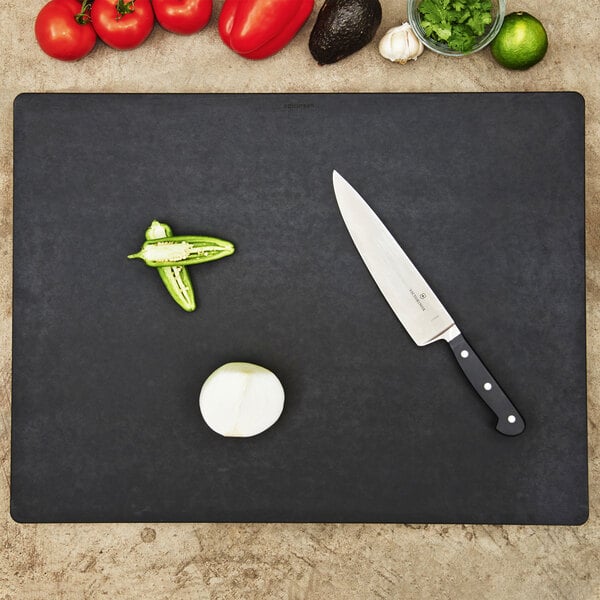 An Epicurean slate Richlite wood fiber cutting board on a counter with a knife and vegetables.