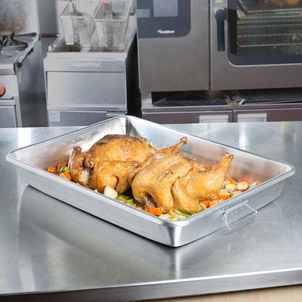 A Vollrath aluminum roasting pan filled with cooked chicken and vegetables on a counter.