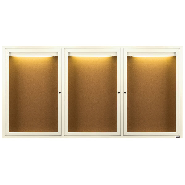 Three white Aarco enclosed bulletin board cabinets with lights.