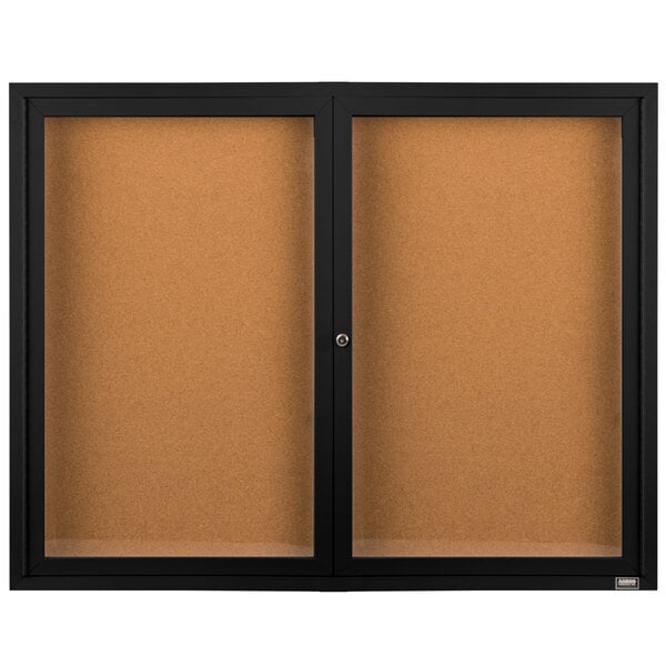 A brown surface with a black border and two glass doors enclosing black bulletin boards.