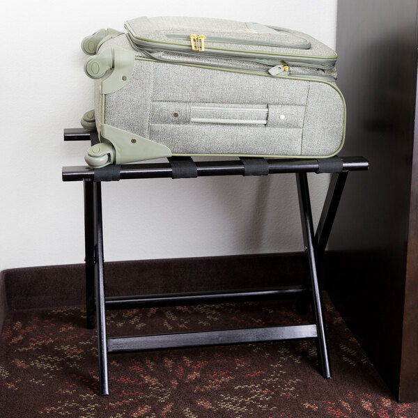 A suitcase on a Lancaster Table & Seating black wood folding luggage rack.