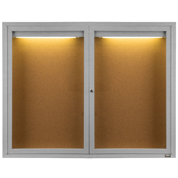 A white Aarco bulletin board cabinet with two lighted doors.