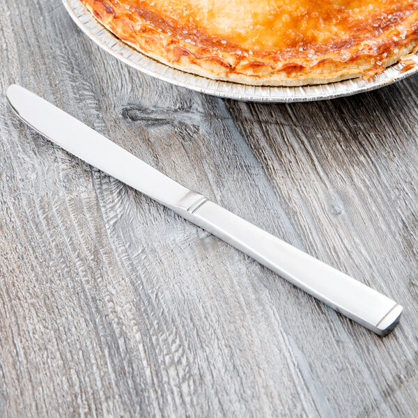 A Libbey stainless steel utility knife with a fluted blade on a table next to a pie.