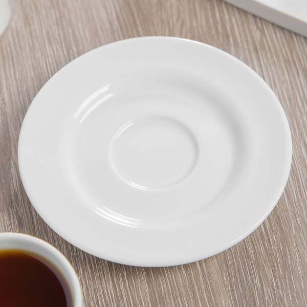 A Schonwald white porcelain saucer with a cup of liquid on it.