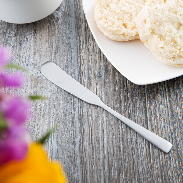 A plate of biscuits with a Libbey stainless steel butter spreader on a table.