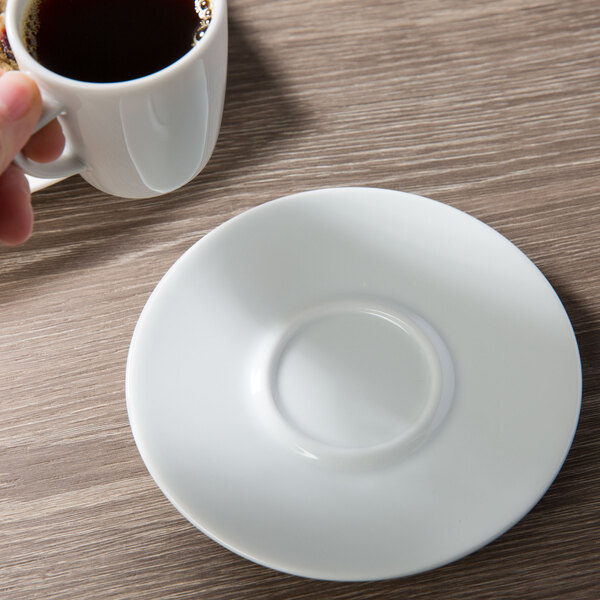 A hand holding a cup of coffee on a Schonwald porcelain saucer.