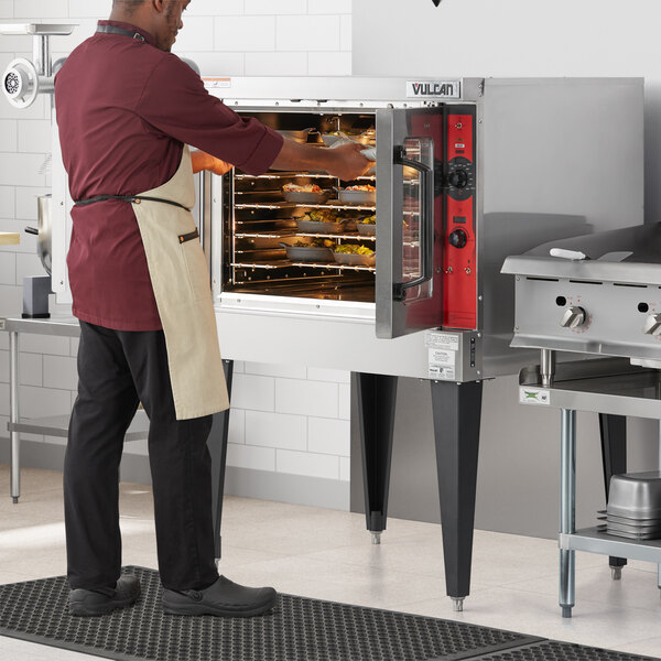 A man in an apron opening a Vulcan convection oven.