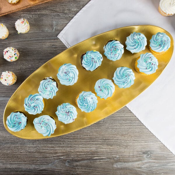 A gold rectangular Thunder Group tray with cupcakes on a table.