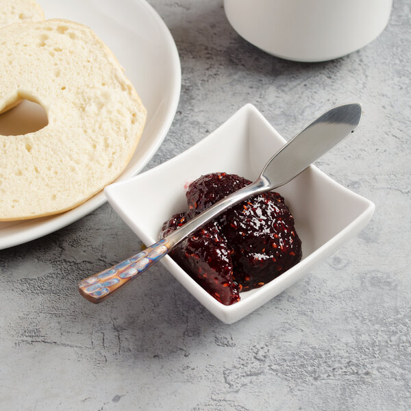 A bowl of jam with a Master's Gauge butter spreader next to a bagel.