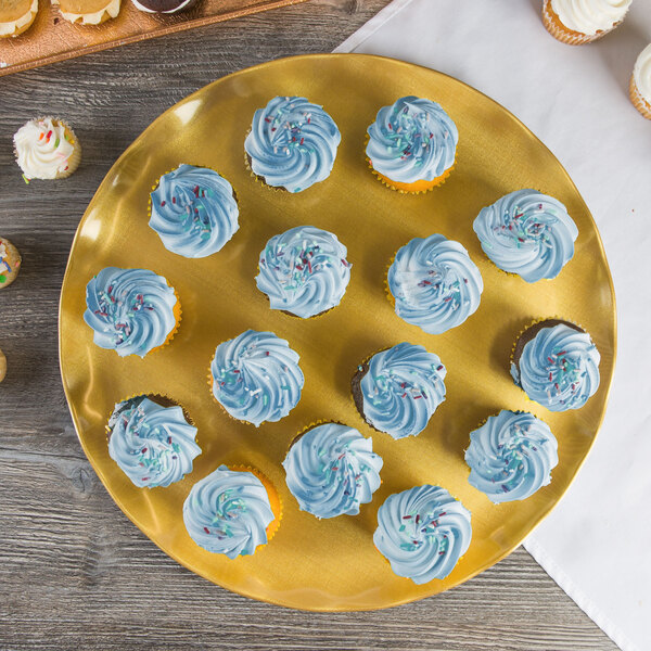 A Thunder Group gold pearl melamine plate with cupcakes with blue and white frosting on a table.