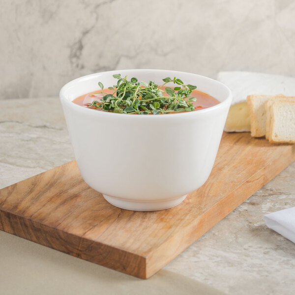 A Villeroy & Boch white porcelain bowl of soup with herbs on top of it.